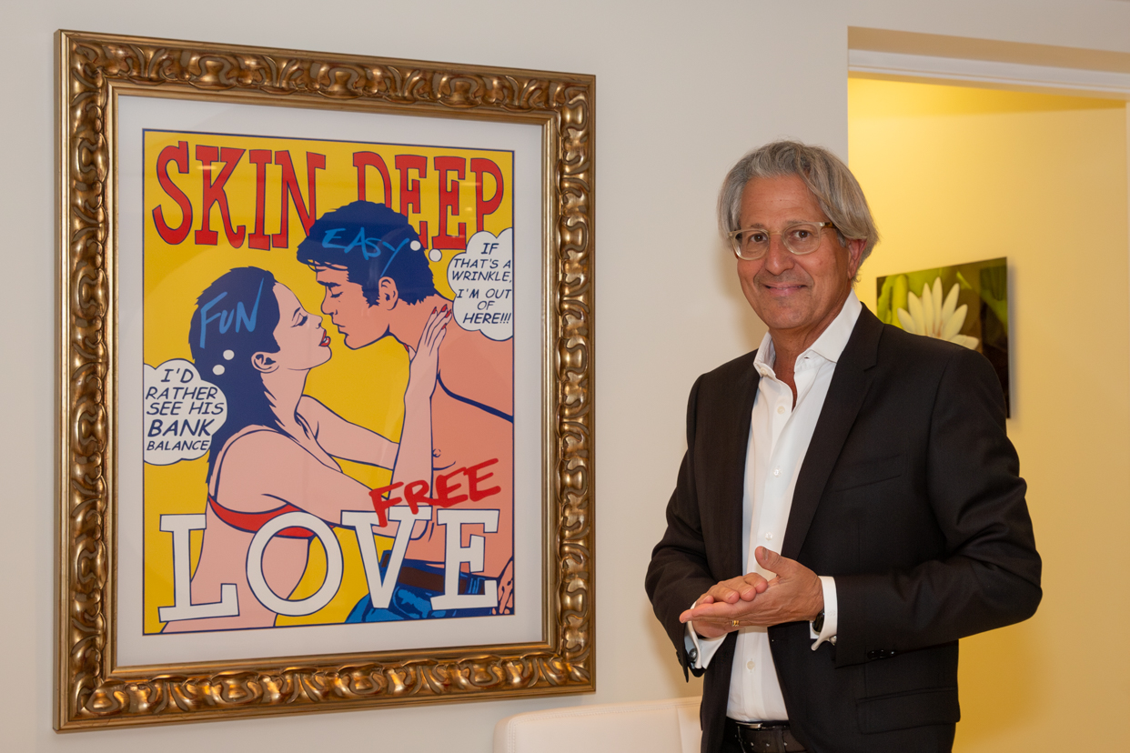 Dr. Alan Serure standing next to a colorful painting in the waiting room of his plastic surgery practice.